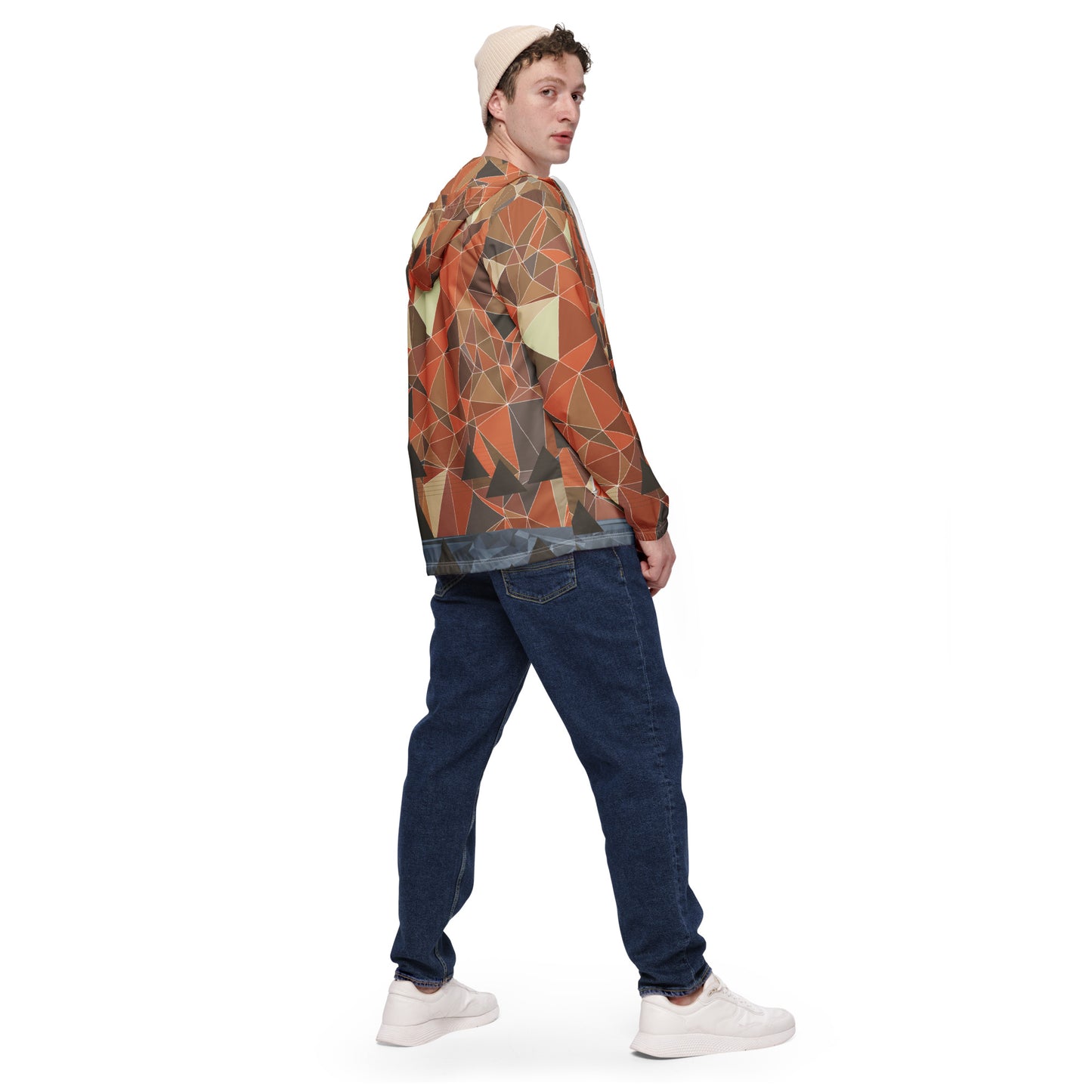 Person wearing a multicolor geometric patterned windbreaker jacket and black jeans on a white background