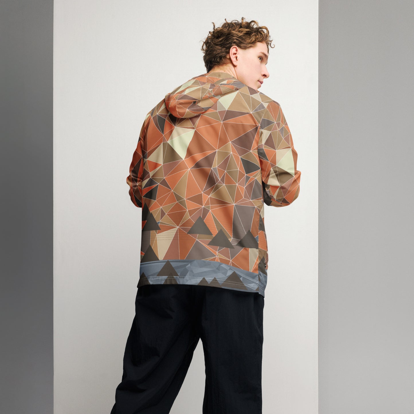 Person wearing a multicolor geometric patterned windbreaker jacket against a plain background