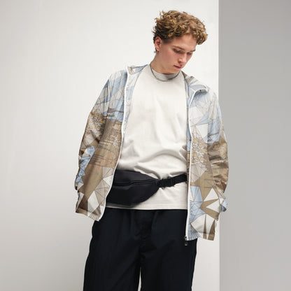 Person wearing an abstract patterned windbreaker over a white sweater with black pants on a plain background