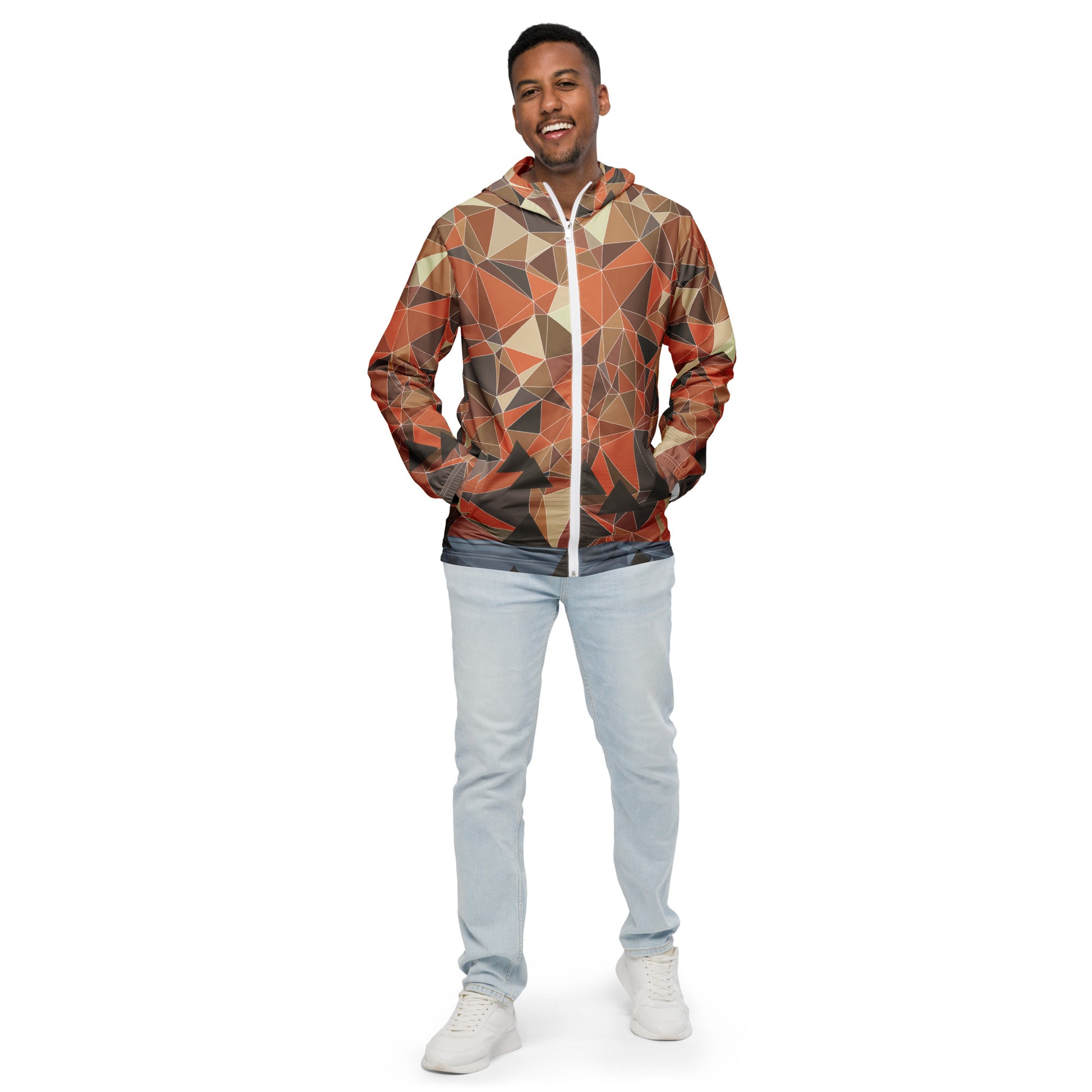 Man wearing a multicolor geometric patterned windbreaker jacket and light blue jeans on a white background