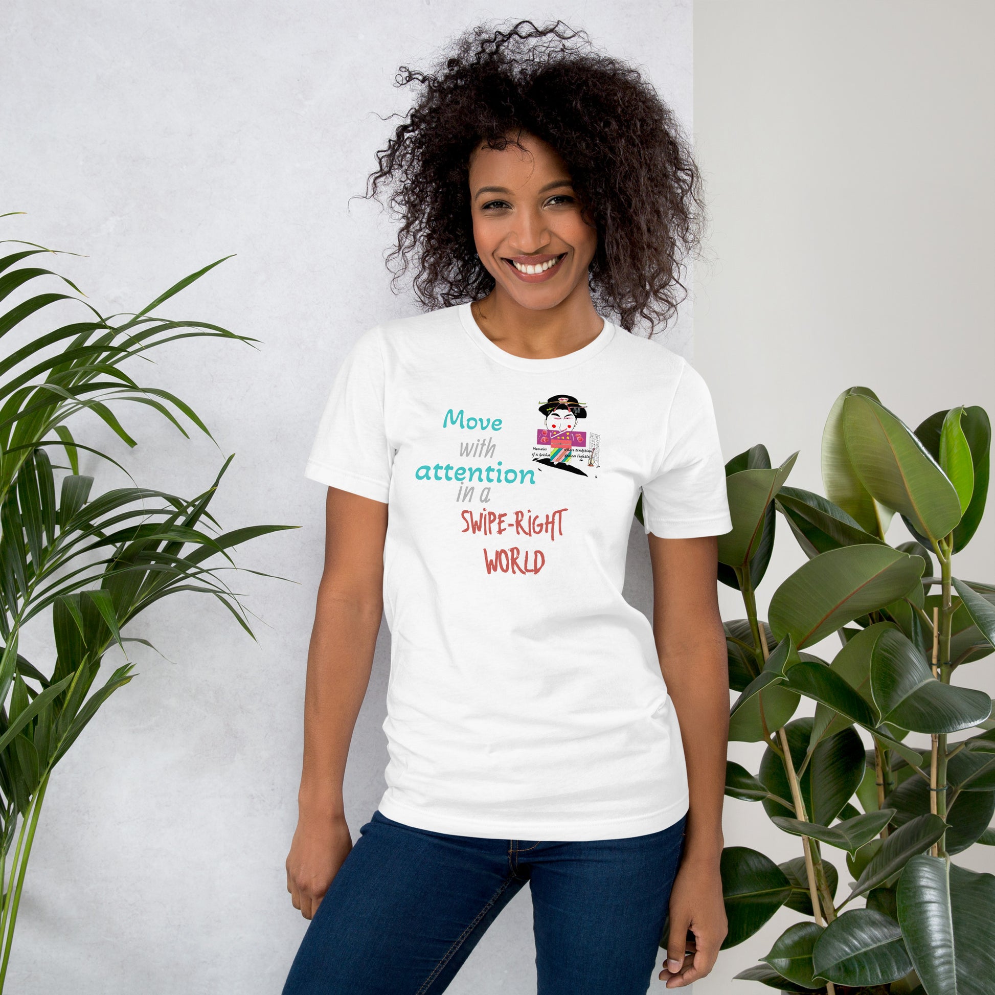 Woman wearing a white t-shirt with colorful text and a playful geisha graphic design, standing between two plants.